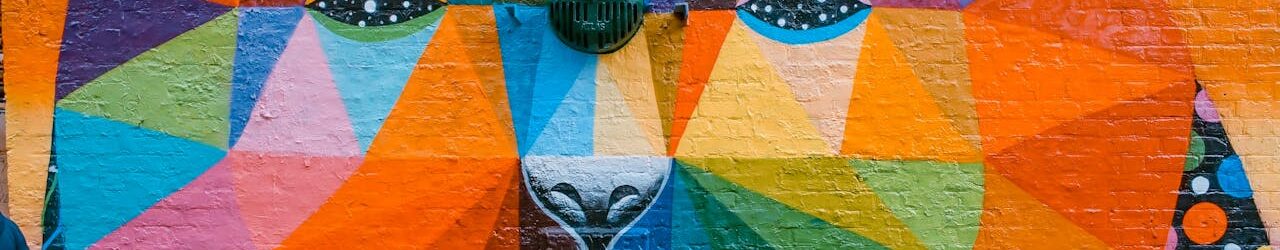 Vibrant geometric mural of a bear on a brick wall in London, showcasing diverse colors and artistic flair.